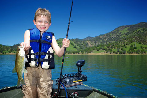 boy in boat holding up fish he caught